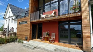 A modern two-story building with a balcony, large windows, and a red facade. - Apartment 'Gästehaus Wüpping 1' with Shared Terrace, Shared Garden and Wi-Fi (Salem)