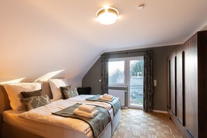 A bedroom with a large bed, a window, and a view of the outside. - Holiday Home 'Haus Cervus' with Private Terrace, Private Garden and Wi-Fi (Hattgenstein)