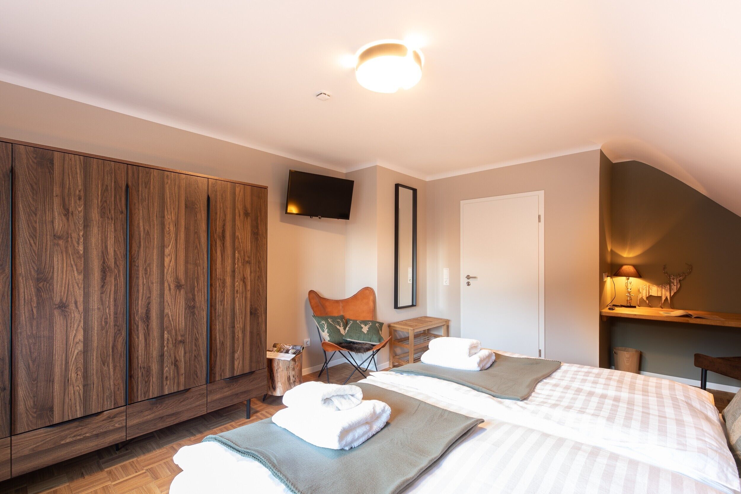 Ein Hotelzimmer mit Holzschrank, Fernseher, Stuhl, zwei Betten und einem kleinen Tisch.