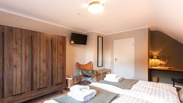 Ein Hotelzimmer mit Holzschrank, Fernseher, Stuhl, zwei Betten und einem kleinen Tisch.