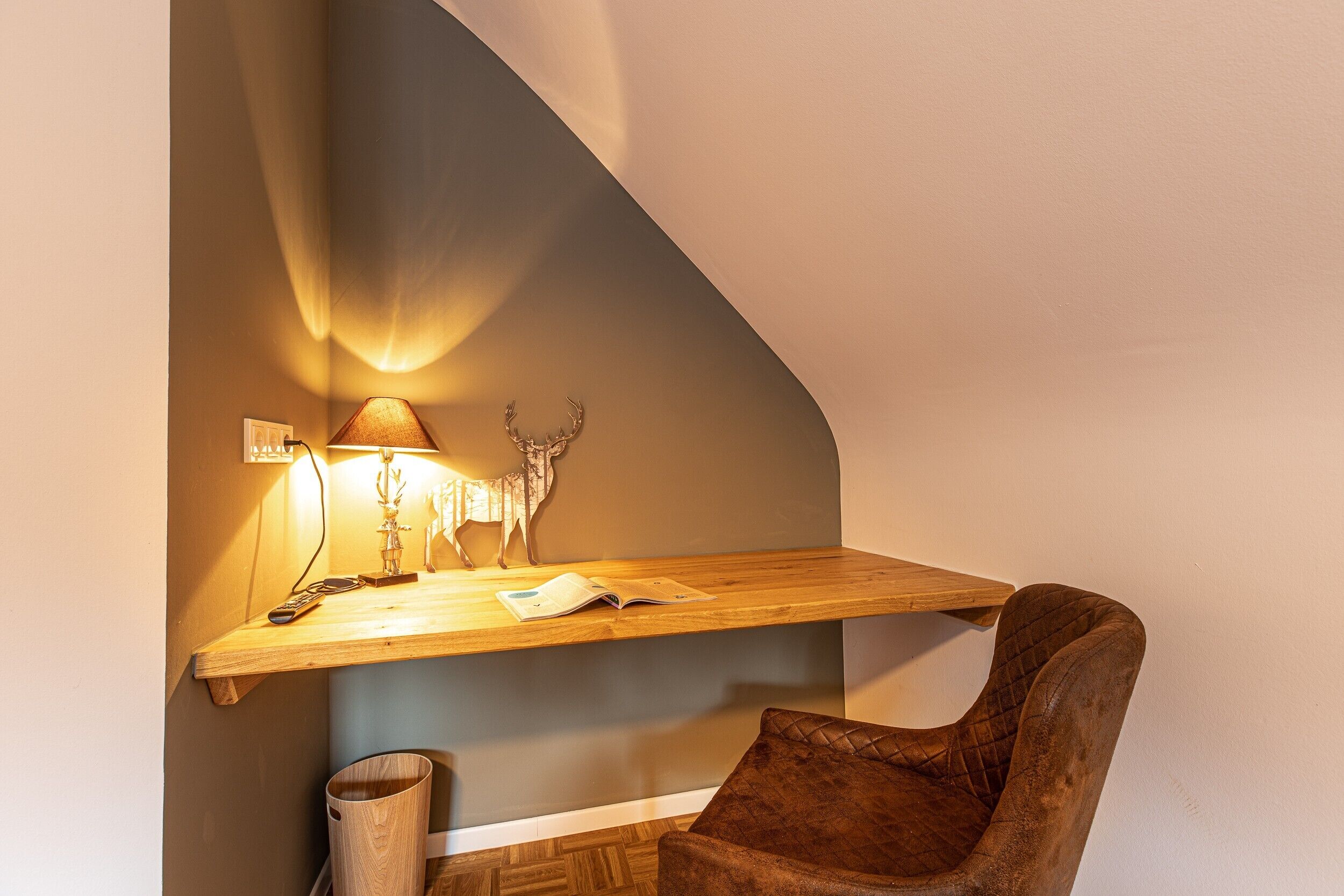 Een knus hoekje met een houten plank, een lamp en een stoel.