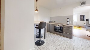 A modern kitchen with a built-in oven, a coffee machine, and a dining area with a bar stool.