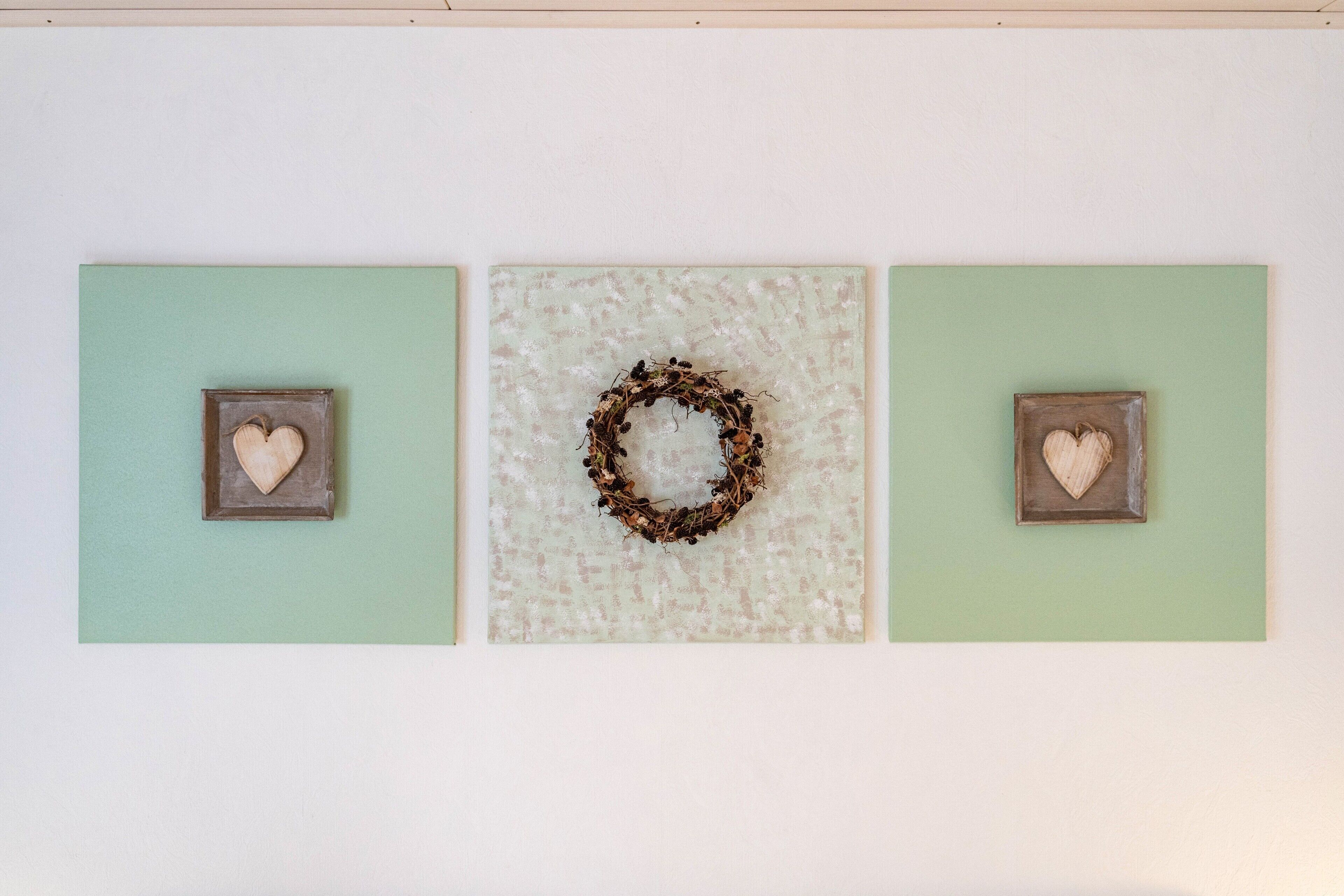 Three square wall art pieces with heart shapes, one with a wreath in the center.