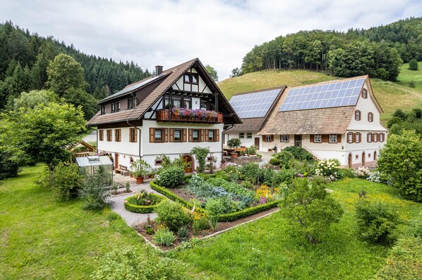 Une grande maison avec un jardin, un balcon orné de fleurs et un panneau solaire sur le toit.