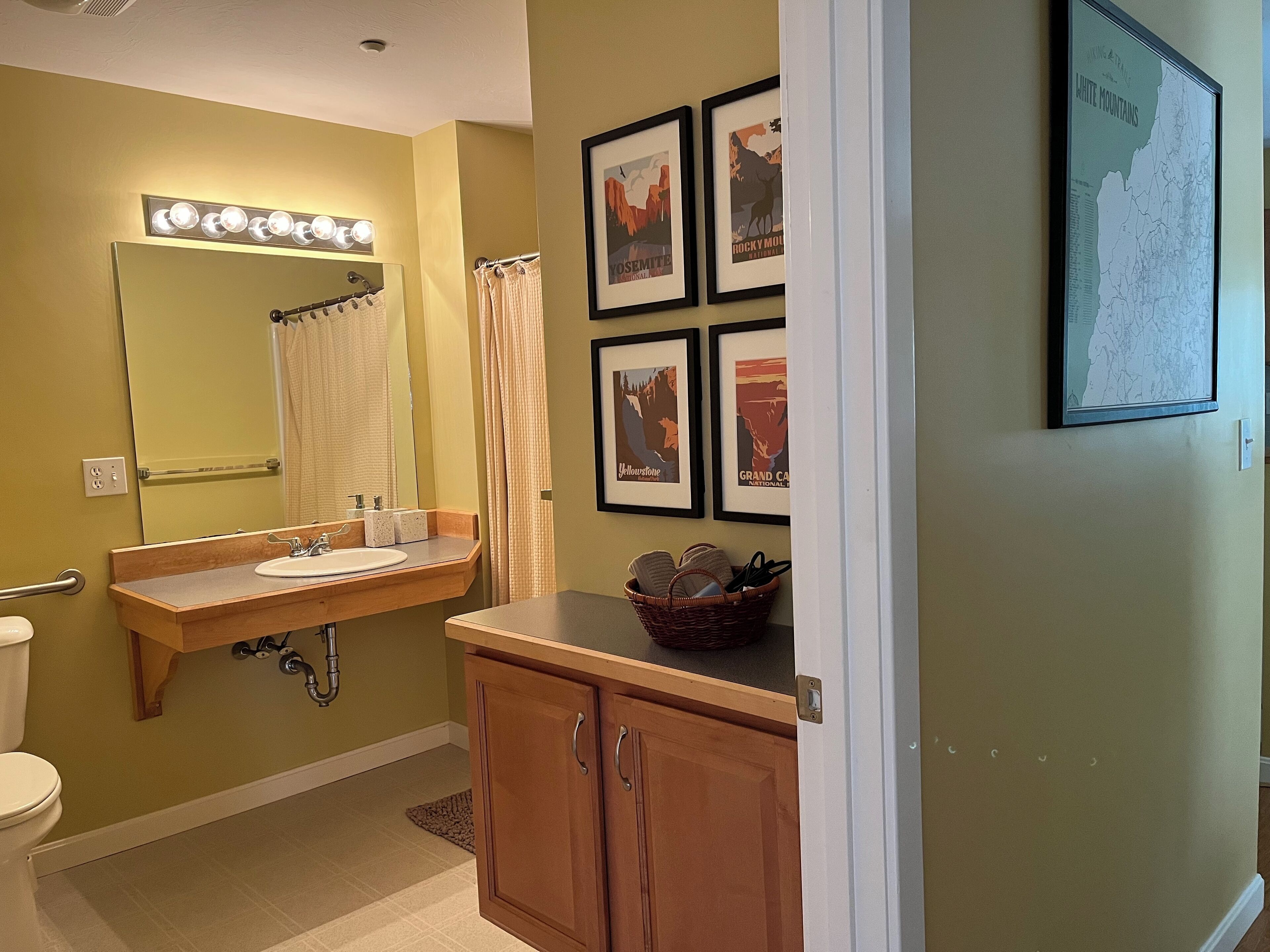 A bathroom with a vanity, sink, mirror, and framed pictures on the wall.