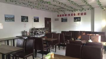 Un comedor con mesas y sillas, una estación de buffet y cuadros en la pared.