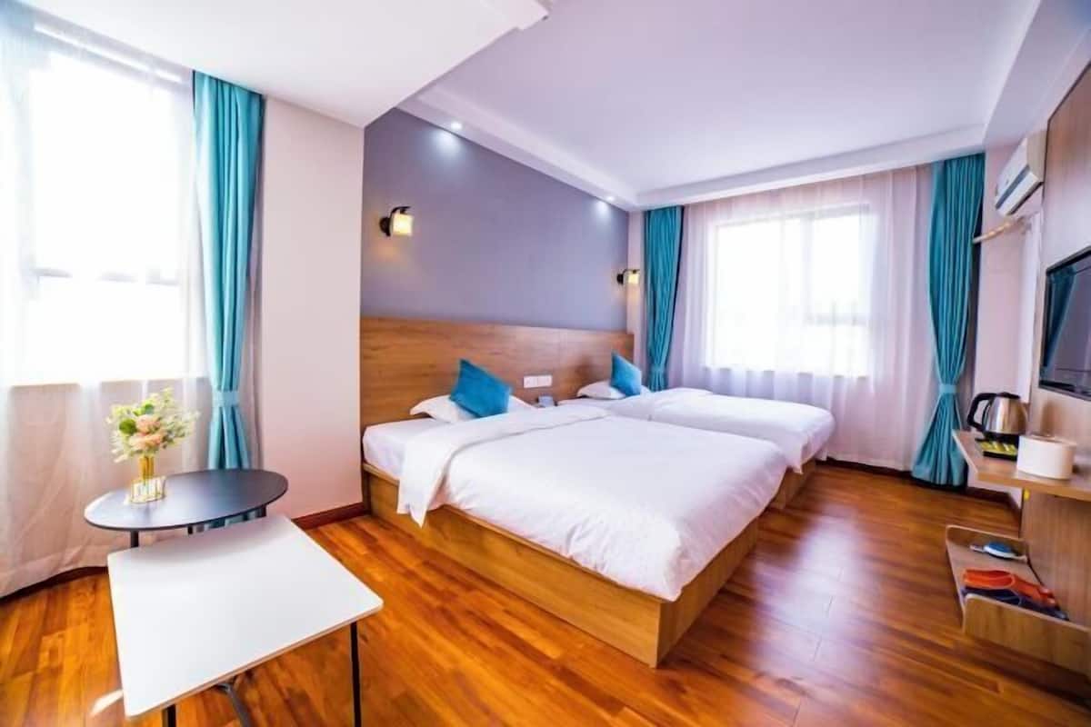 A hotel room with two beds, a small table, and a TV.