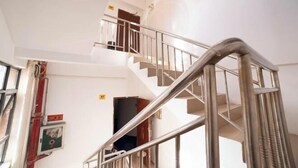 Un interior de varios niveles con una escalera, una puerta con la etiqueta “4F” y un cuadro eléctrico en la pared.