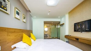 Habitación de hotel con una cama grande, televisor montado en la pared y cuadros enmarcados.