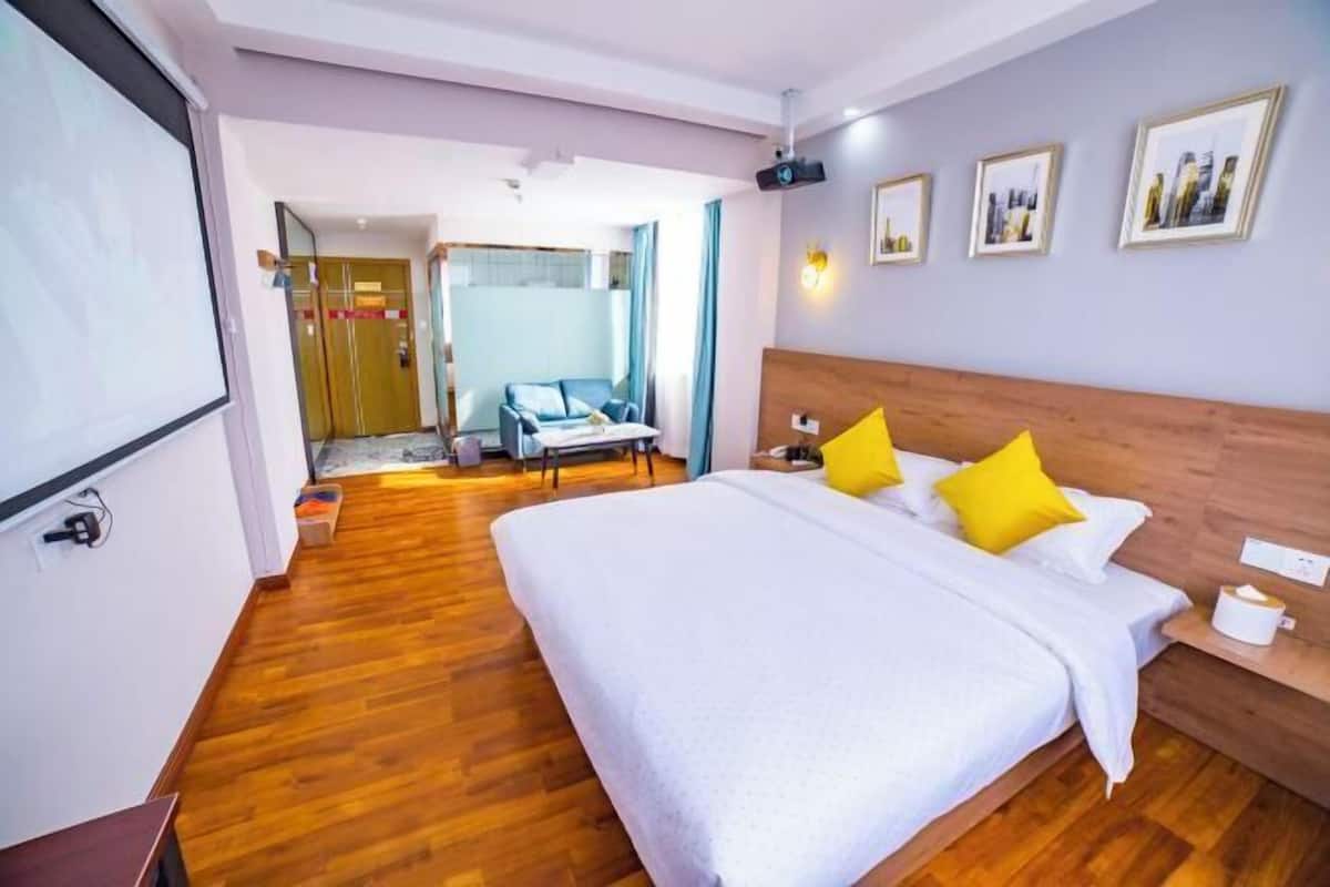 A hotel room with a large bed, a wooden headboard, and a desk with a chair.