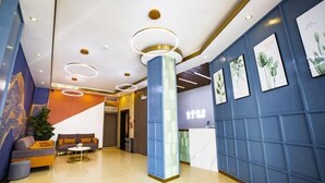Un vestíbulo moderno con una pared azul, un mostrador de recepción y una zona de estar con un sofá y una mesa de centro.