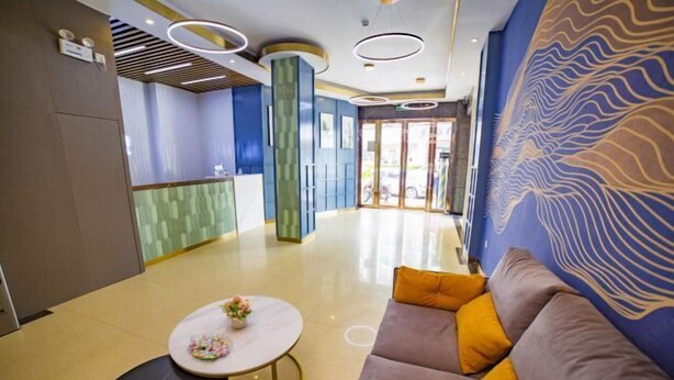 Un lobby moderno con un mostrador de recepción, un sofá con cojines y un muro con diseño.
