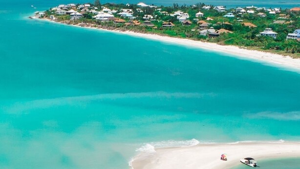 An aerial view of a coastal area with a white sandy beach, clear turquoise waters, and a small island with buildings. - Welcome to Corallo house - Heated Pool - Pet friendly - Relaxing Gateway  (Cape Coral)