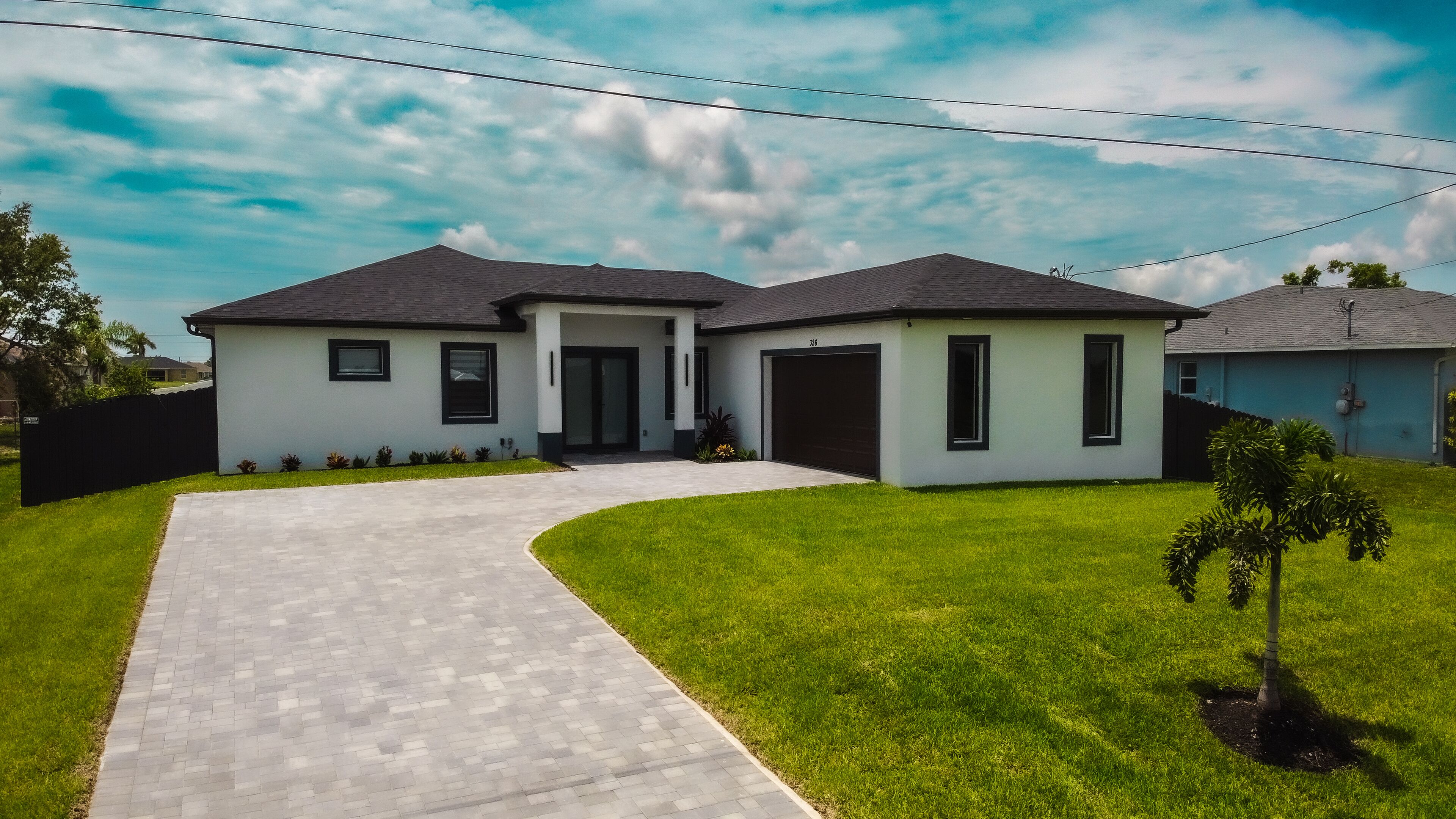 Een modern huis met twee verdiepingen, met een oprit naar de garage.