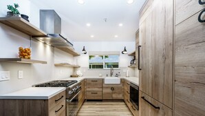 Una cucina moderna con mobili in legno, un fornello a gas e una finestra con vista sul verde.