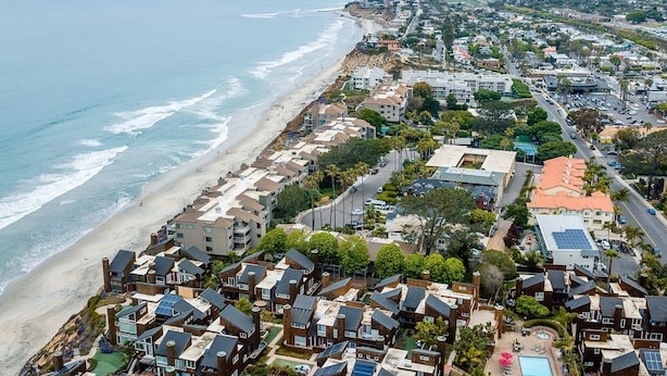 Una zona residenziale sul lungomare, con case, spiaggia e strada.