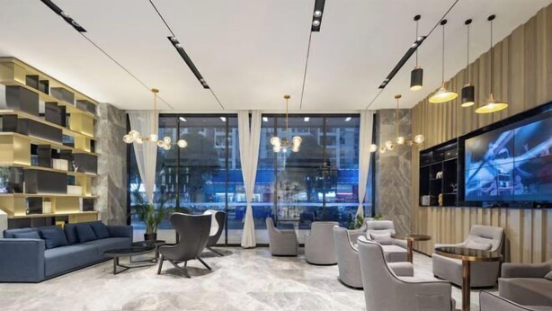 A modern lobby with a sofa, armchairs, a TV, and a bookshelf. - Echarm Hotel (Chongzuo Youyi Avenue South Railway Station) (Chongzuo)