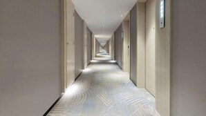A long, narrow hotel corridor with a patterned floor and doors on both sides. - Echarm Hotel (Chongzuo Youyi Avenue South Railway Station) (Chongzuo)