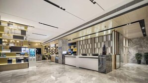 A modern hotel lobby with a marble floor, a reception desk, and a digital information kiosk. - Echarm Hotel (Chongzuo Youyi Avenue South Railway Station) (Chongzuo)
