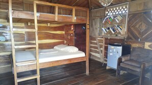 Una cabaña rústica con una cama nido, un escritorio pequeño y una silla.