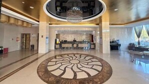 Eine Hotelhalle mit Empfangstresen, einer Kronleuchter und einem kreisförmigen Bodenmuster.