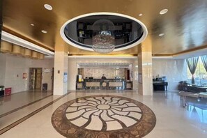 A hotel lobby with a reception desk, a chandelier, and a circular floor design. - Boyu Hotel (Karamay)