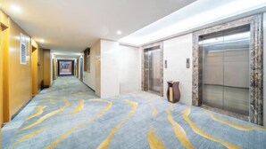 A hotel hallway with a marble floor, elevators, and a reception desk. - Boyu Hotel (Karamay)