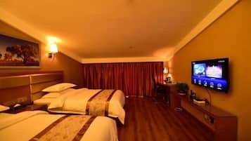 A hotel room with two beds, a TV on the wall, a desk with a lamp, and a painting on the wall.