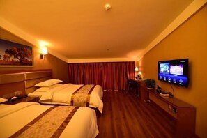 Habitación de hotel con dos camas, un televisor en la pared, un escritorio con lámpara y un cuadro.