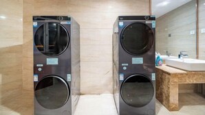 A modern bathroom with two wall-mounted washing machines, a wooden vanity with a sink, and a large mirror. - Boyu Hotel (Karamay)