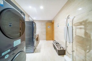 A hotel laundry room with multiple washing machines and dryers, a telephone, and a door leading to another room.