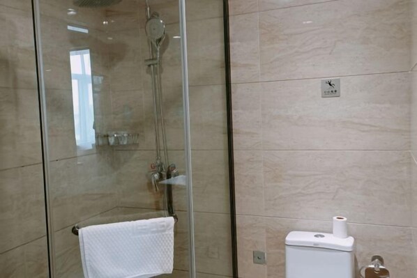 A bathroom with a glass-enclosed shower, a towel rack, and a toilet with a paper towel dispenser. - Boyu Hotel (Karamay)