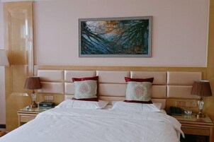 Quarto de hotel com uma cama grande, duas mesas de cabeceira, uma cabeceira e um quadro na parede.