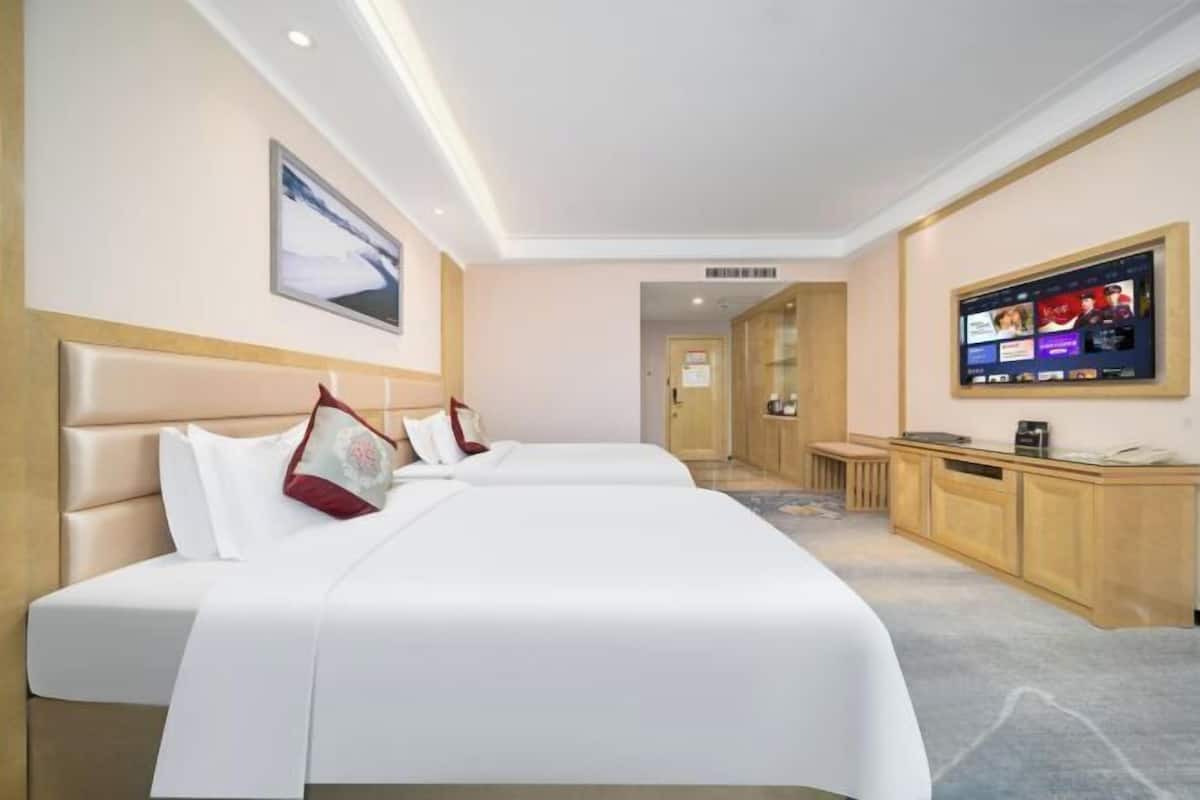 Una habitación de hotel con una cama grande, un televisor y un armario de madera.
