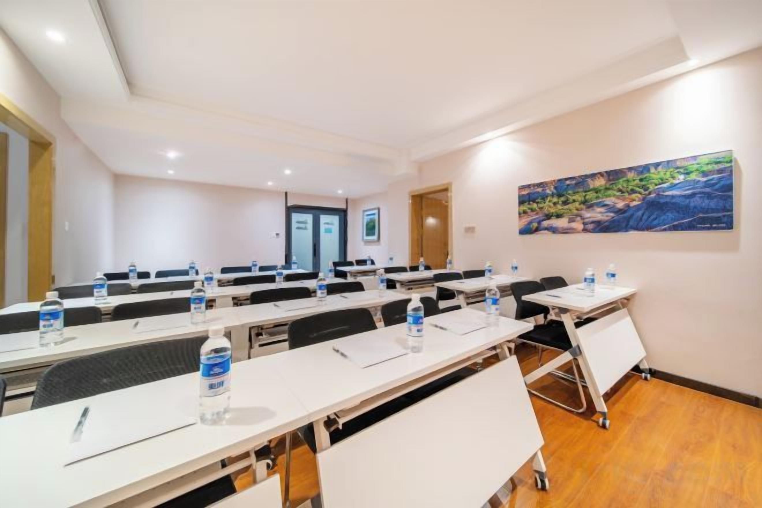 A conference room with multiple tables, water bottles, and a cart.