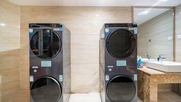 A modern bathroom with two wall-mounted washing machines, a wooden vanity, and a large mirror.