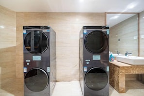 A modern bathroom with two wall-mounted washing machines, a wooden vanity, and a large mirror.