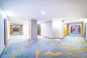 A hotel corridor with a carpeted floor, doors on both sides, and a central pillar. - Boyu Hotel (Karamay)