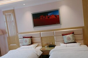 Habitación de hotel con dos camas, una mesita y un cuadro en la pared.