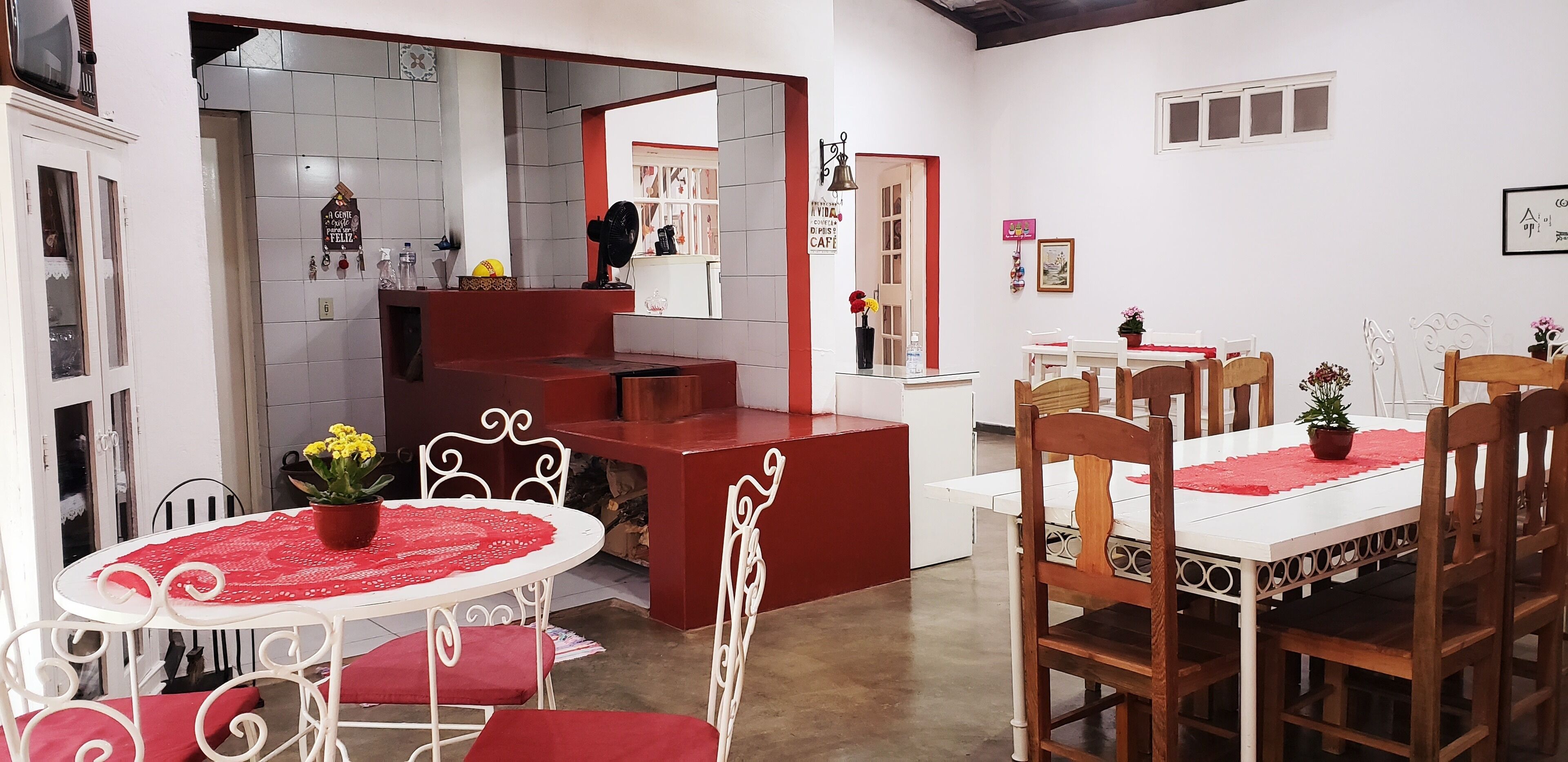 A dining area with a white table and red chairs, a red counter, and a small potted plant.