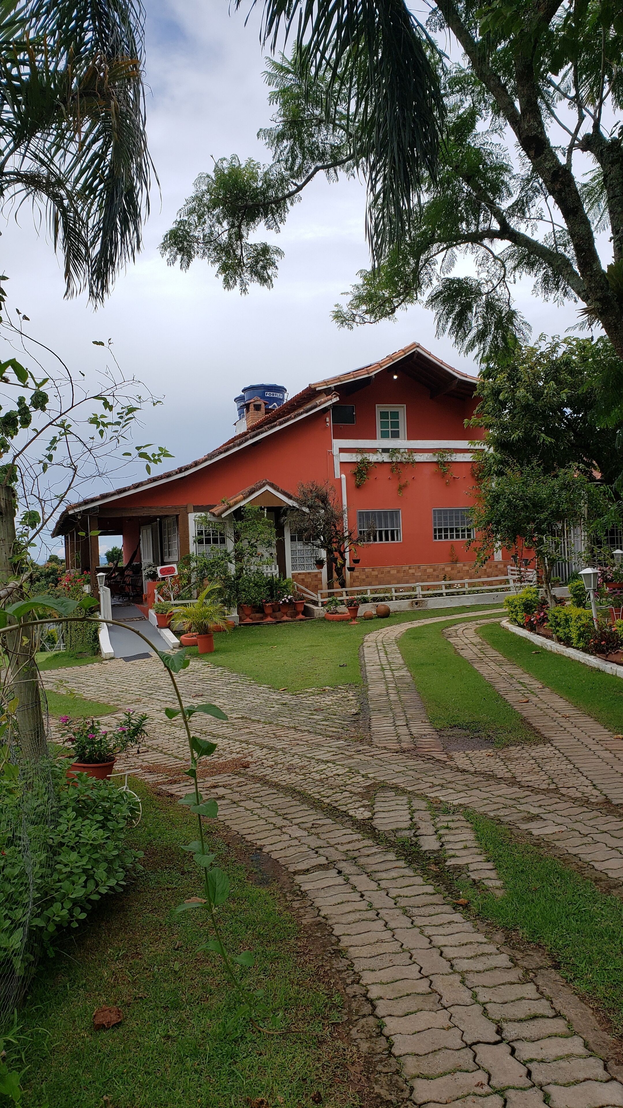 A red house with a paved driveway and a garden.