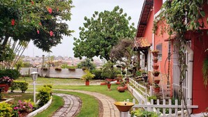 A garden with a winding path, potted plants, and a white picket fence. - Pousada Calu (Cunha)