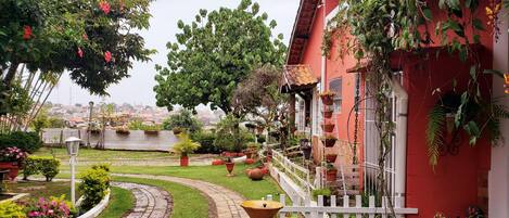 A garden with a winding path, potted plants, and a white picket fence.