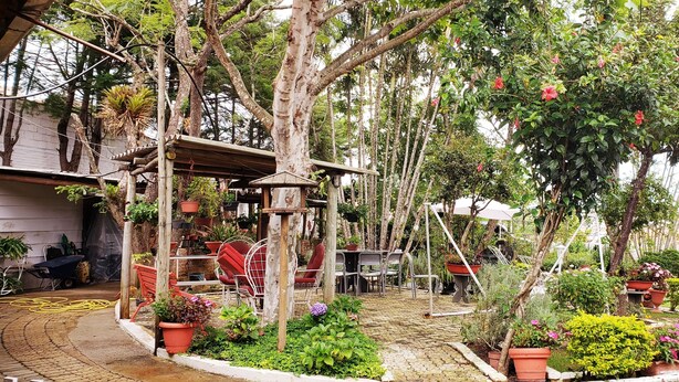 A garden patio with potted plants, a swing set, and outdoor furniture. - Pousada Calu (Cunha)