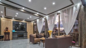 A modern living room with a fireplace, comfortable seating, and a view of a balcony. - Pomegranate Homestay (Lijiang)