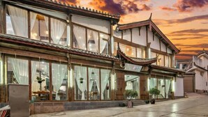 A traditional building with large windows, a tiled roof, and a visible entrance. - Pomegranate Homestay (Lijiang)