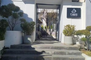 A building entrance with a sign, steps, and potted plants. - Pomegranate Homestay (Lijiang)