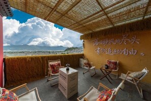 A terrace with a view of the sea, wicker furniture, and a wall with Chinese characters.