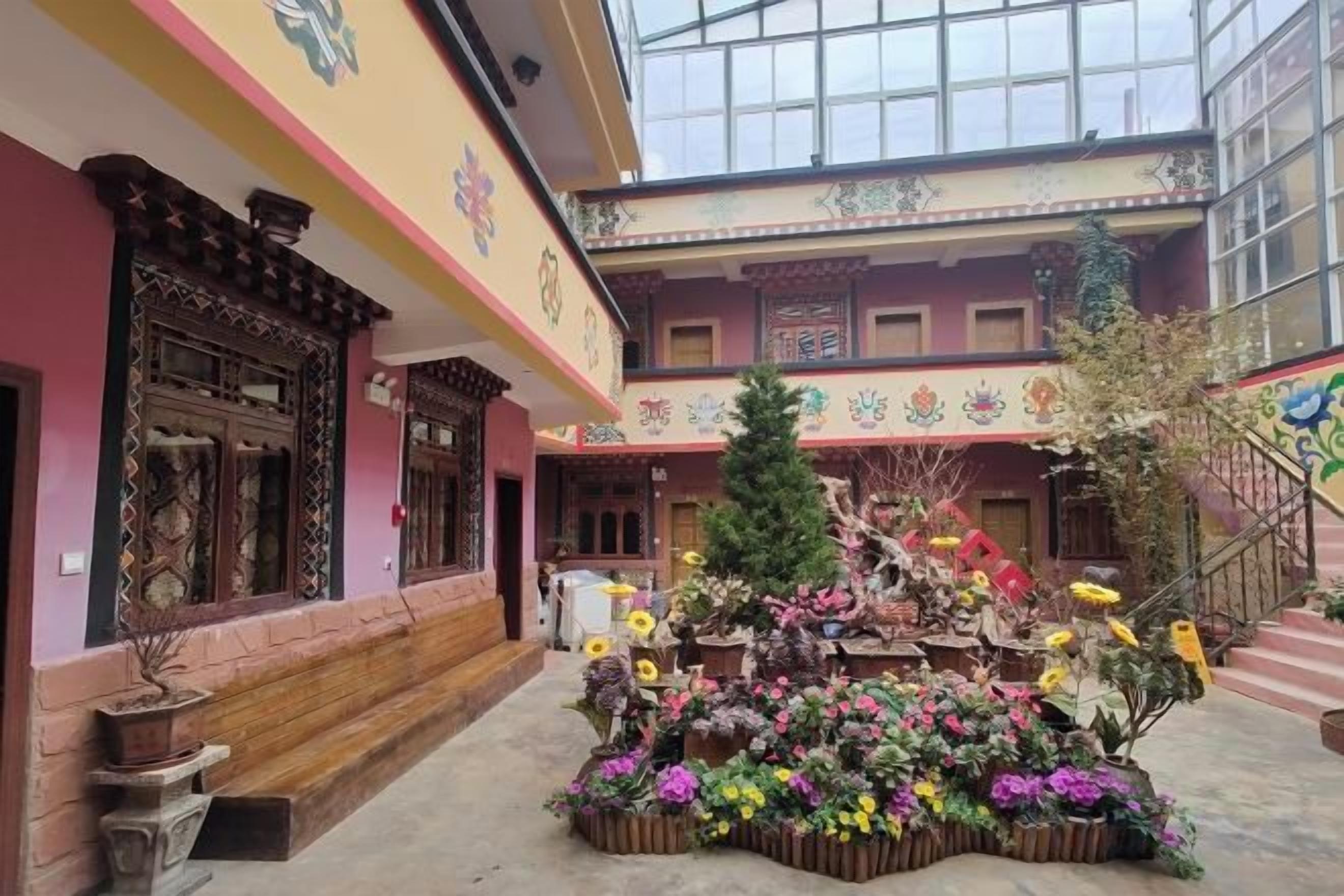 Un patio con un arreglo floral central, una escalera y un edificio con detalles arquitectónicos tradicionales.