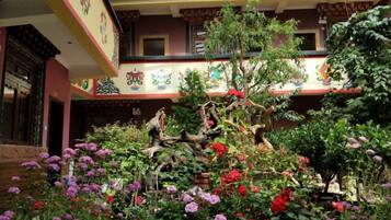 A traditional building with a courtyard, a small tree, and colorful flowers.